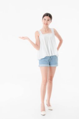Stüdyo portre rahat yaz kıyafetler, kot şort ve gevşek kolsuz bluz, geniş bir gülümseme, genç güzel, çekici Asya kadının ayakta, izole beyaz arka plan üzerinde poz