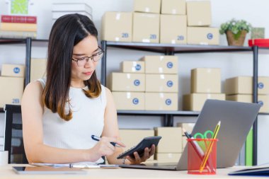 Mutlu, genç, güzel, Asya iş Bayan, uzun siyah saçlı, gözlük, gülümseyen, ayakta silah başlangıç ev ofis arka plan ile onun masanın arkasında geçti geçici moda giyen portresi