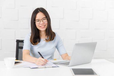 Genç, güzel, Asya mimar, giyen gözlük Oda kalem elinde, Toplantı inşaat sahasında alarak not notepad, defter ile üzerinde çalışma tablet ve smartphone ve kahve Kupası arka plan