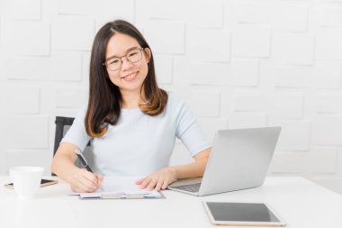 Genç, güzel, Asya mimar, giyen gözlük Oda kalem elinde, Toplantı inşaat sahasında alarak not notepad, defter ile üzerinde çalışma tablet ve smartphone ve kahve Kupası arka plan