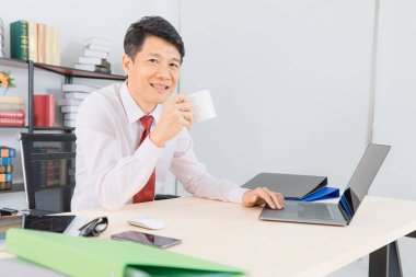 Orta portresi yaşlı, onun başlangıç office, office arka plan ile onun başarı ile mutlu çalışan yakışıklı, Asya, işadamı, koyu kırmızı kravat, Beyaz gömlekli