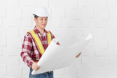 Turuncu, sarı yansıtıcı Emanet yelek ve kask, planları, inşaat site ofiste çalışan kontrol giyen Asya yakışıklı mimar, kot pantolon ve ekose desenli gömlek, orta yaşlı