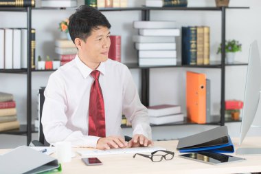 Bilgisayar ve ofis arka plan ile e-posta gönderme başlangıç ofisinde çalışan mutlu orta yaşlı, yakışıklı, Asya, işadamı, koyu kırmızı kravat, Beyaz gömlekli