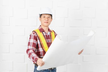 Turuncu, sarı yansıtıcı Emanet yelek ve kask, planları, inşaat site ofiste çalışan kontrol giyen Asya yakışıklı mimar, kot pantolon ve ekose desenli gömlek, orta yaşlı