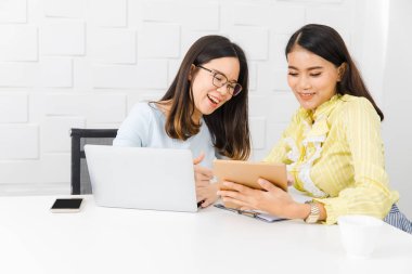 İnşaat site ile toplantı odası beyaz tuğla duvar arka plan ile tablet ve defter, kullanarak, proje yönetimi zaman çizelgeleri hakkında tartışıyor iki genç, güzel, Asya mimarlar, gayri resmi toplantı,