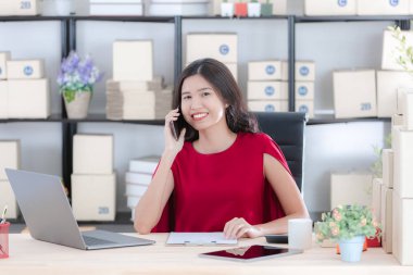 İş istasyonunda oturan yüz, gülümseyen genç güzel, çekici Asya işkadını Kırmızı elbiseli portresi e-postalar, modern başlangıç office arka plan denetimi sırasında kahve sabah fincan keyfini çıkarın