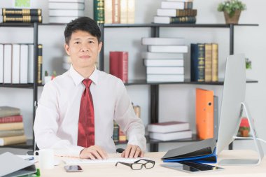 Bilgisayar ve ofis arka plan ile e-posta gönderme başlangıç ofisinde çalışan mutlu orta yaşlı, yakışıklı, Asya, işadamı, koyu kırmızı kravat, Beyaz gömlekli