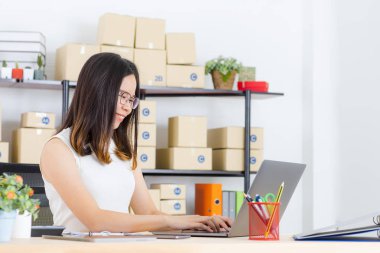 Mutlu, genç, güzel, Asya iş Bayan, uzun siyah saçlı, gözlük, gülümseyen, ayakta silah başlangıç ev ofis arka plan ile onun masanın arkasında geçti geçici moda giyen portresi