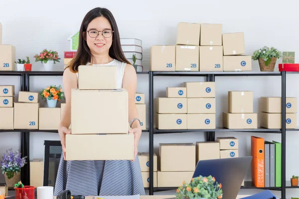 Happy, young, beautiful, Asian business lady, long black hair, wearing eyeglasses, in casual fashion, check delivery tracking reference number on notebook, with startup home office background