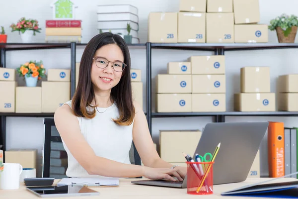 Mutlu, genç, güzel, Asya iş Bayan, uzun siyah saçlı, gözlük, gülümseyen, ayakta silah başlangıç ev ofis arka plan ile onun masanın arkasında geçti geçici moda giyen portresi