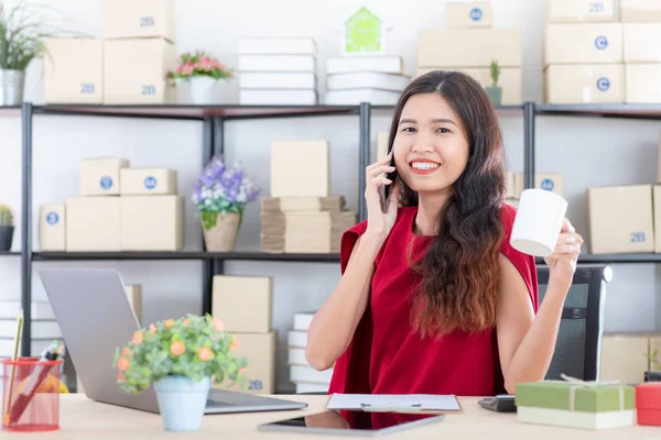 Gamzeli, stil Kırmızı elbiseli, uzun siyah saçları ile gülümseyen genç güzel, Asya iş kadını doz sabah kahvesi, tablet, onun moda başlangıç office arka plan ile haber okuma keyfini çıkarın.