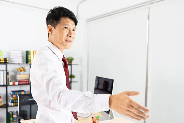 Close up portrait of middle aged, handsome, Asian, businessman, in white shirt, necktie, black pants posing handshake sign for greeting and welcoming sign, on isolated white background