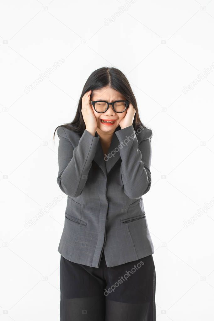Studio portrait of young Asian woman, long black hair, wearing glasses, in gray suit, hold her head, crying, grieving over unexpected bad news on isolated white background