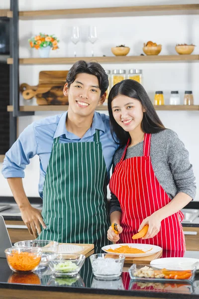 Ásia casal no avental poses para câmara no cozinha — Fotografia de Stock