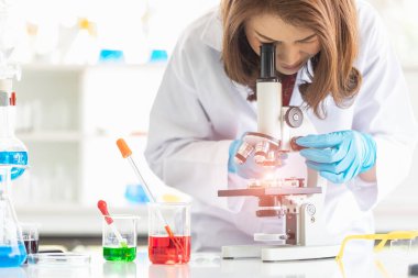 Bilim adamı mikroskoba bakıyor.