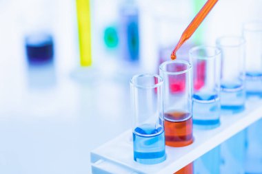 Test tüplerine kırmızı sıvı bırakan biri.