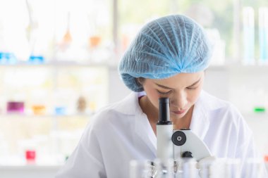 Bilim adamı mikroskoba bakıyor.