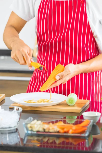 Homem rala a cenoura em tiras, na cozinha — Fotografia de Stock