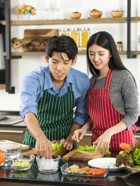 Asiático pareja en delantal hacer un ensalada juntos —  Fotos de Stock