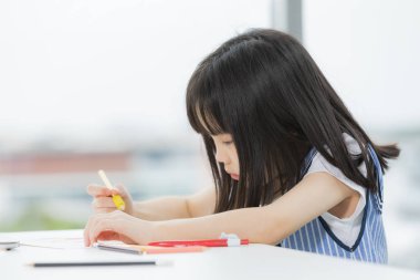 Asyalı kız ciddi çizer.