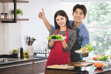 Önlüklü çift birlikte salata yapıyor.