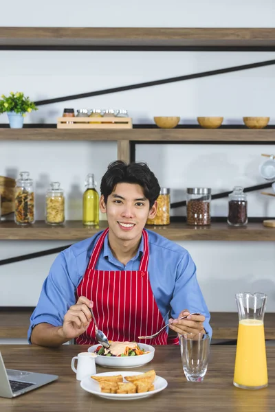 주방에서 샐러드를 먹는 아시아 남자. — 스톡 사진