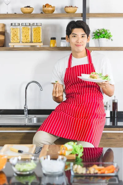 Homem asiático come salada no balcão da cozinha — Fotografia de Stock