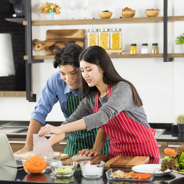 Asiático pareja en delantal hacer un ensalada juntos —  Fotos de Stock