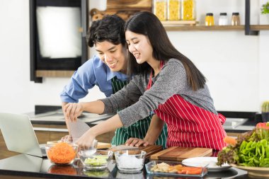  Apron Asyalı çift mutfakta dizüstü bilgisayar kullanır