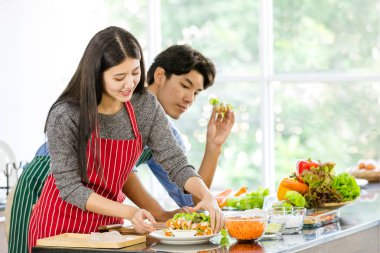 Önlüklü çift birlikte salata yapıyor.