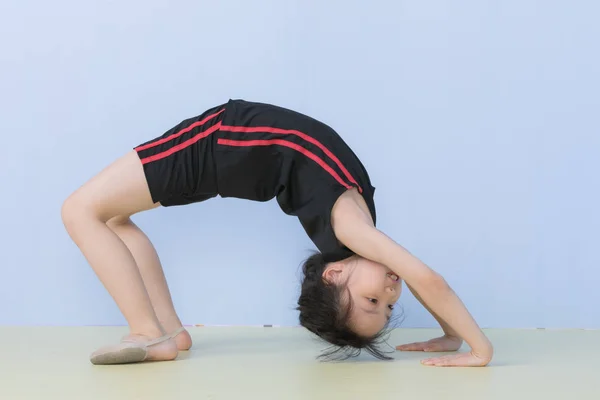 Aziatisch meisje in sportkleding poseren een brug pose — Stockfoto