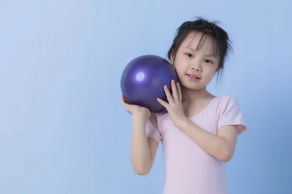 Азійська дівчинка в рожевій сукні тримає м'яч. — стокове фото