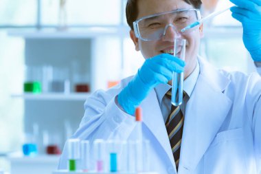 Bilim adamı mavi sıvıyı test tüpüne atıyor..