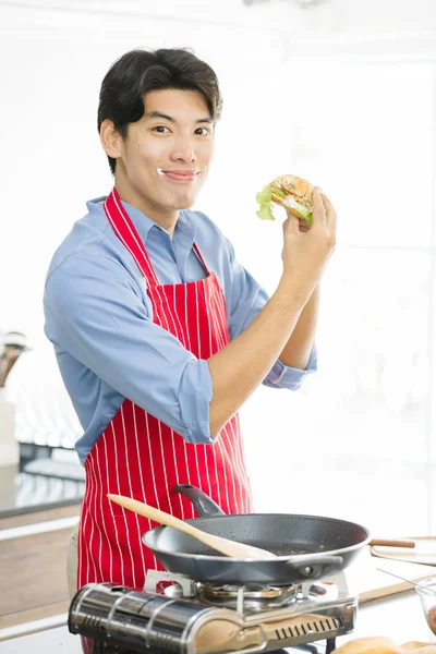 Asiático hombre, él sostiene un hamburguesa y golpes hasta —  Fotos de Stock