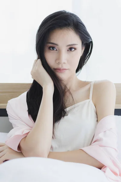 Asiatisk kvinna modell sitter och poserar på sängen — Stockfoto