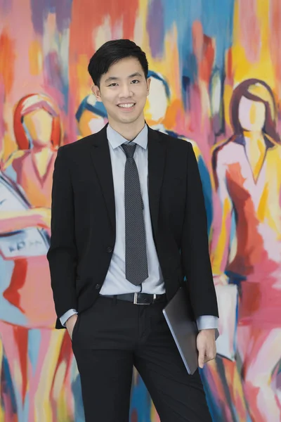 Jonge Aziatische zakenman in zwart pak staande — Stockfoto