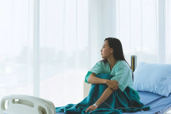 Patiënt zit op het bed en kijkt uit het raam.. — Stockfoto