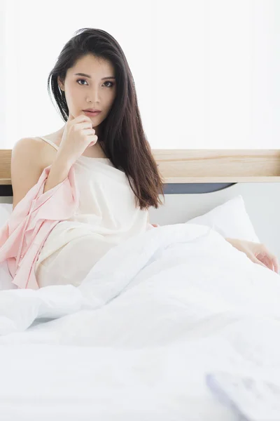 Asiatisk kvinna modell sitter och poserar på sängen — Stockfoto
