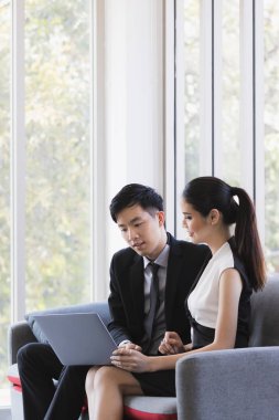 Ofiste dizüstü bilgisayar kullanan Asyalı işadamları