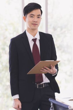 Asyalı İşadamı ofisinde duruyor ve poz veriyor