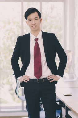 Asyalı İşadamı ofisinde duruyor ve poz veriyor