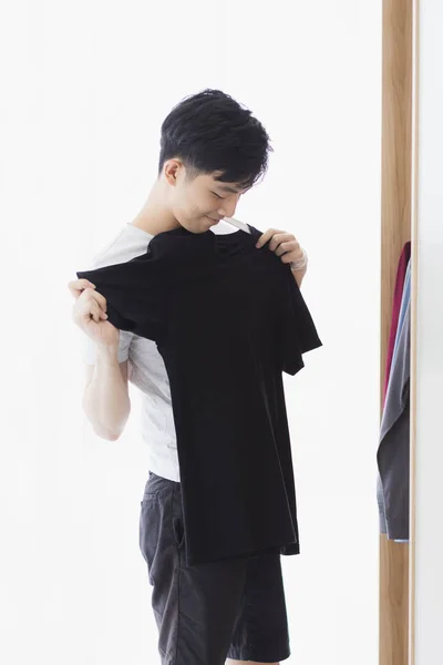 Uomo raccoglie una t-shirt nera dal guardaroba — Foto Stock