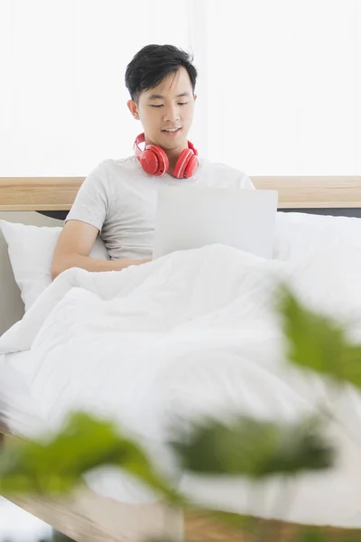Hombre asiático con auriculares rojos, escuchando música — Foto de Stock