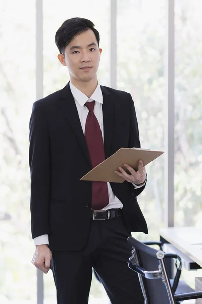 Asiatisk affärsman stående och poserar i ämbetet — Stockfoto
