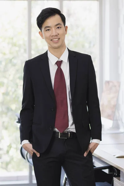 Азиатский бизнесмен, стоящий и позирующий в офисе — стоковое фото