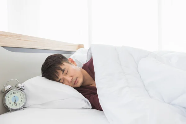 Aziatisch man liggen op een kant op het bed — Stockfoto