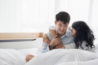 Çift yatakta oturur, birbirlerine sevgiyle sarılırlar.