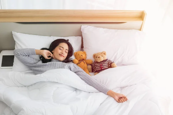 Asian woman sleeps on bed with two teddy bear