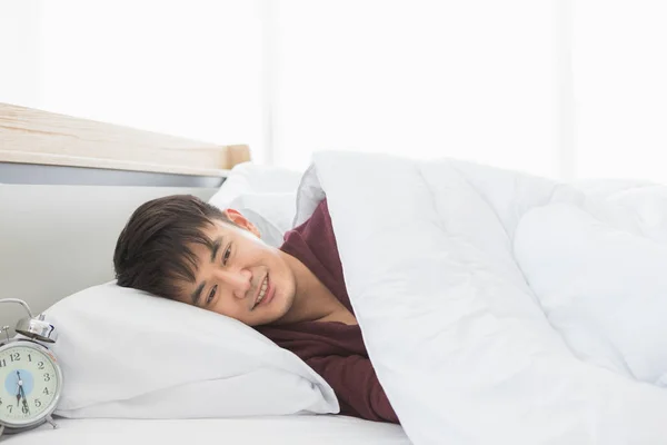 Aziatisch man liggen op een kant op het bed — Stockfoto