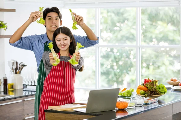 Coppia in grembiule fare insalata rotoli insieme — Foto Stock